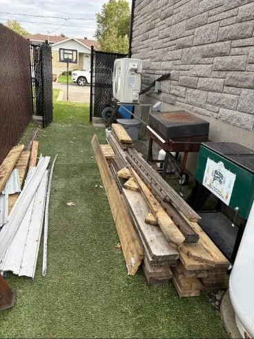 Avant: bois de construction et revêtement empilés dans la cour arrière